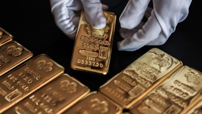 An employee handles one kilogram gold bullion at the YLG Bullion International Co. headquarters in Bangkok, Thailand