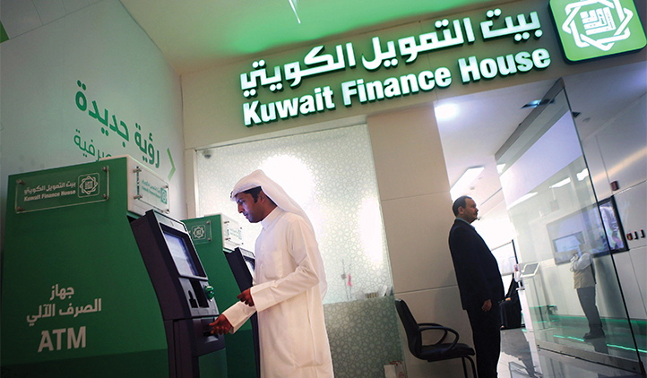 A man removes money from an ATM at a branch of Kuwait Finance House