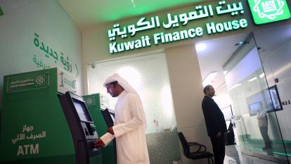 A man withdraws cash from an ATM at a Kuwait Finance House branch