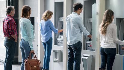People queueing at a row of ATMs