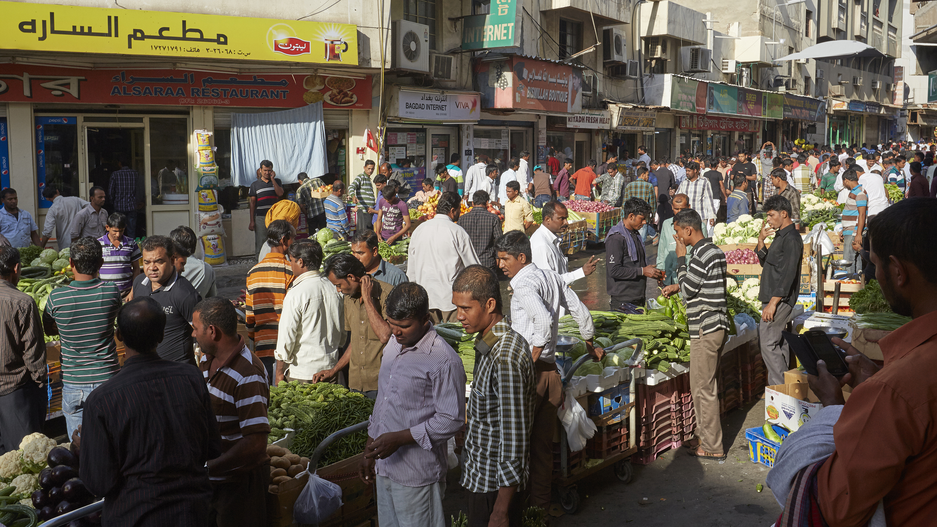 A busy Bahraini market street, with stalls selling a variety of foodstuffs.