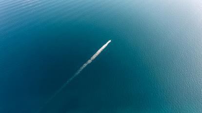 A boat leaves a wake in a vast expanse of ocean