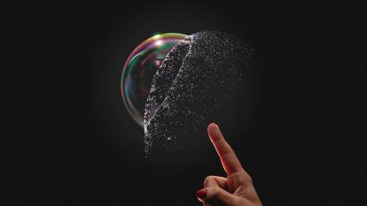 A bubble bursting after being popped by a finger