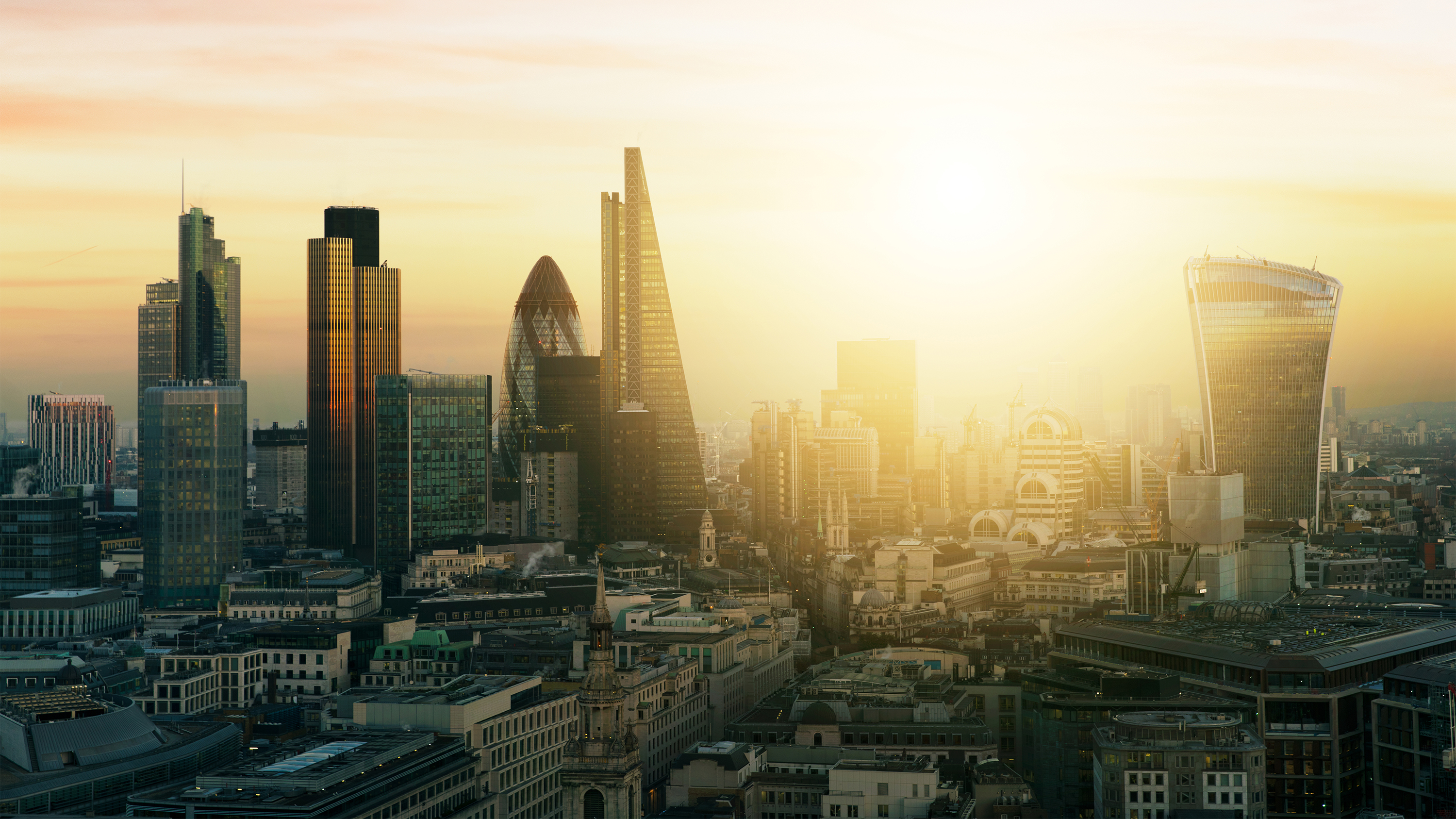 A cityscape image of the city of London, with the sun low in the sky