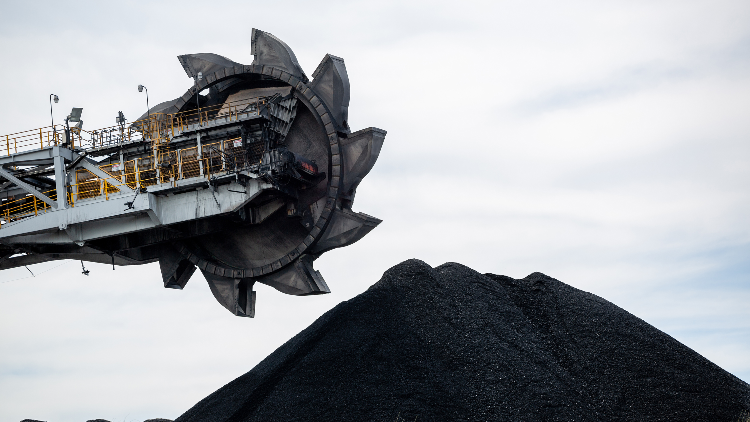 A coal loader above a large pile of coal.