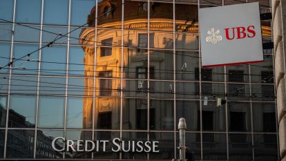 The UBS and Credit Suisse logos on a reflective glass building