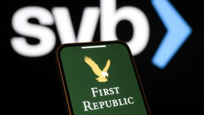 The First Republic Bank logo on a phone screen in the foreground, with the SVB logo in the background.