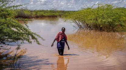 A farmer crosses a flooded area in farmland near Garissa, Kenya