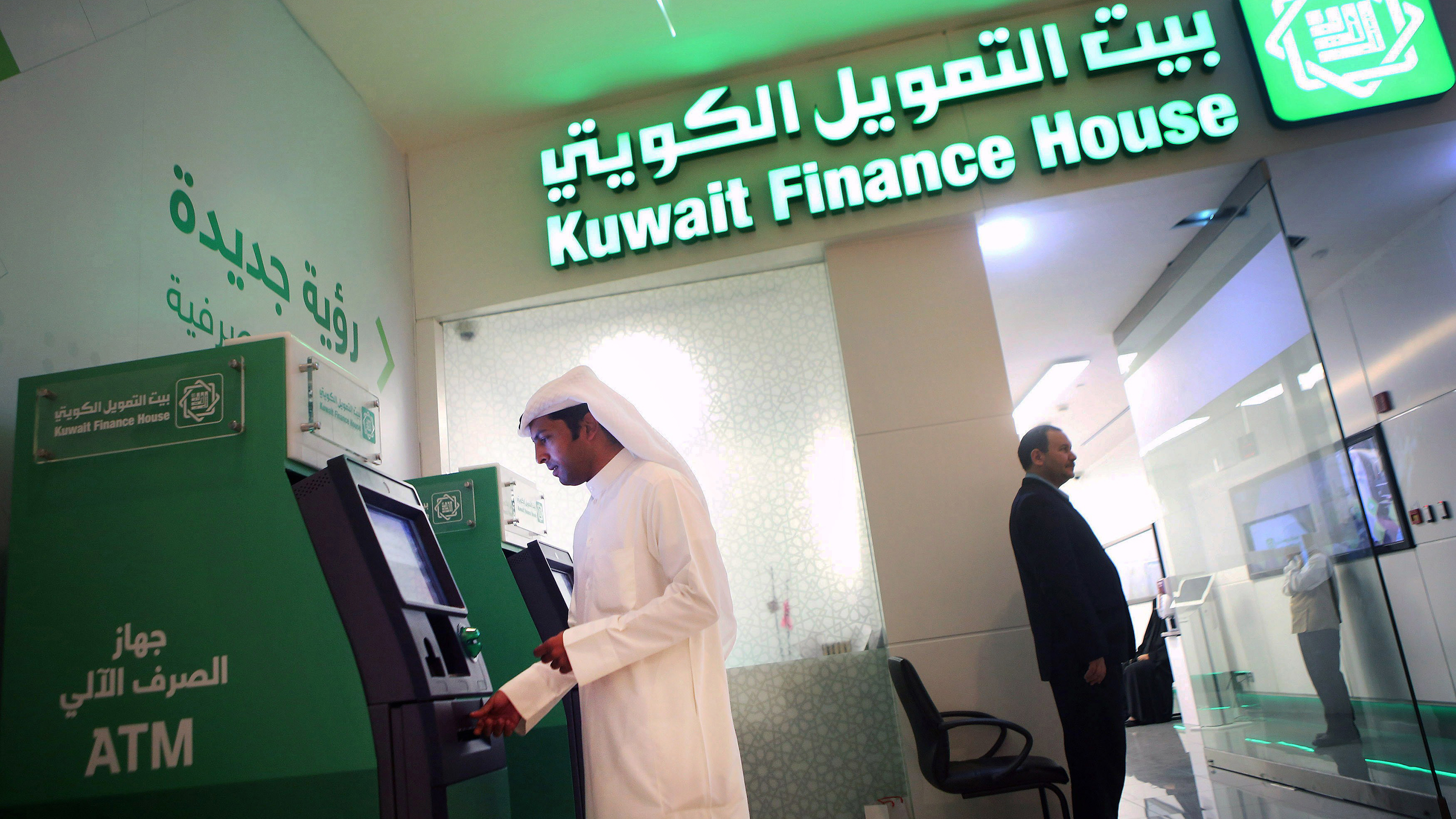 A man withdraws cash from an ATM at a Kuwait Finance House branch.