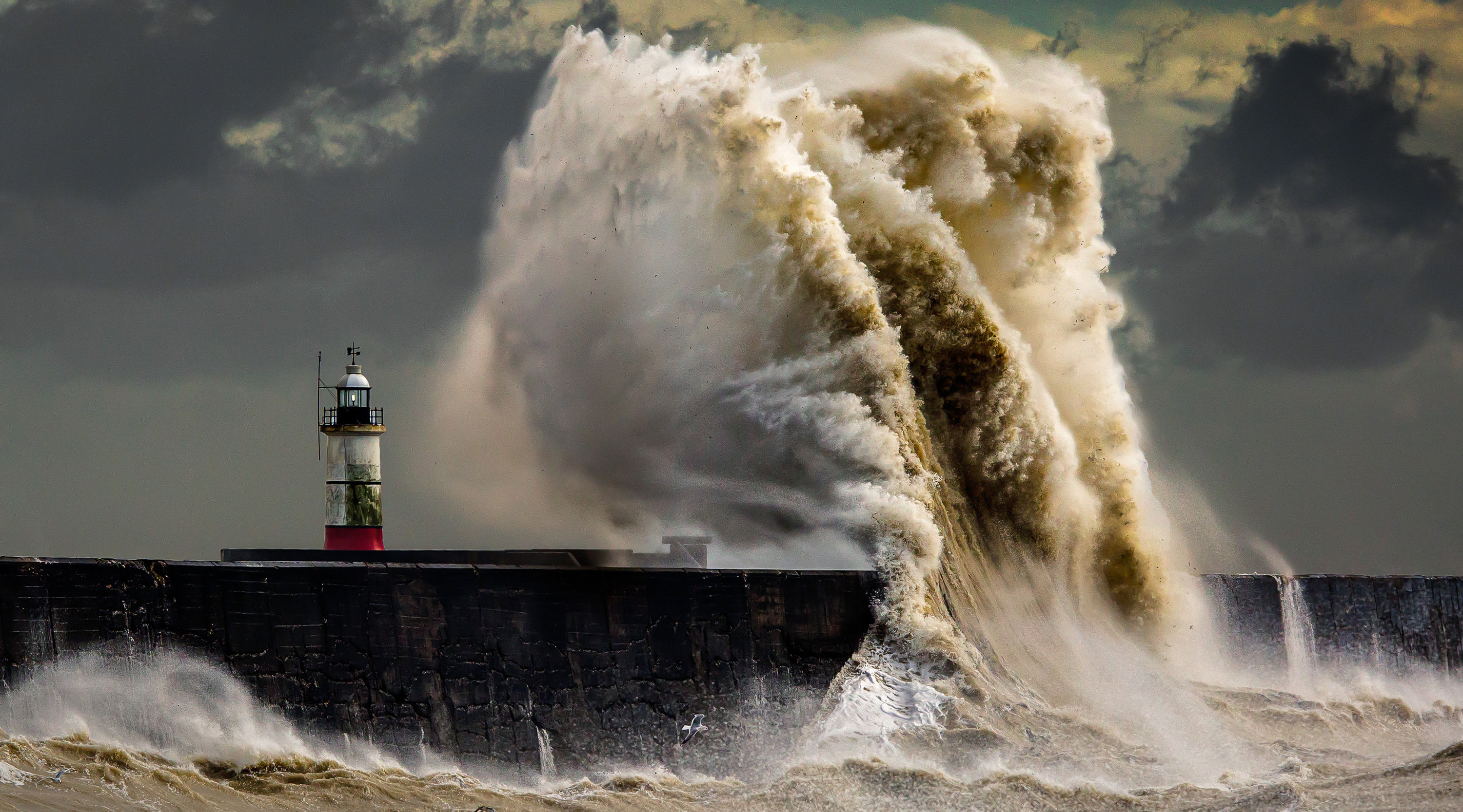 A lighthouse being buffeted by waves in a storm.