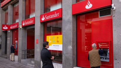Customers queue at an ATM outside a branch of Santander bank