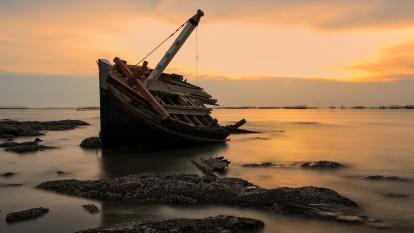A shipwreck on a beach during sunset