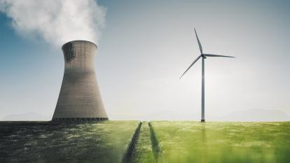An image of a field with a cooling tower emitting steam and a wind turbine next to it.